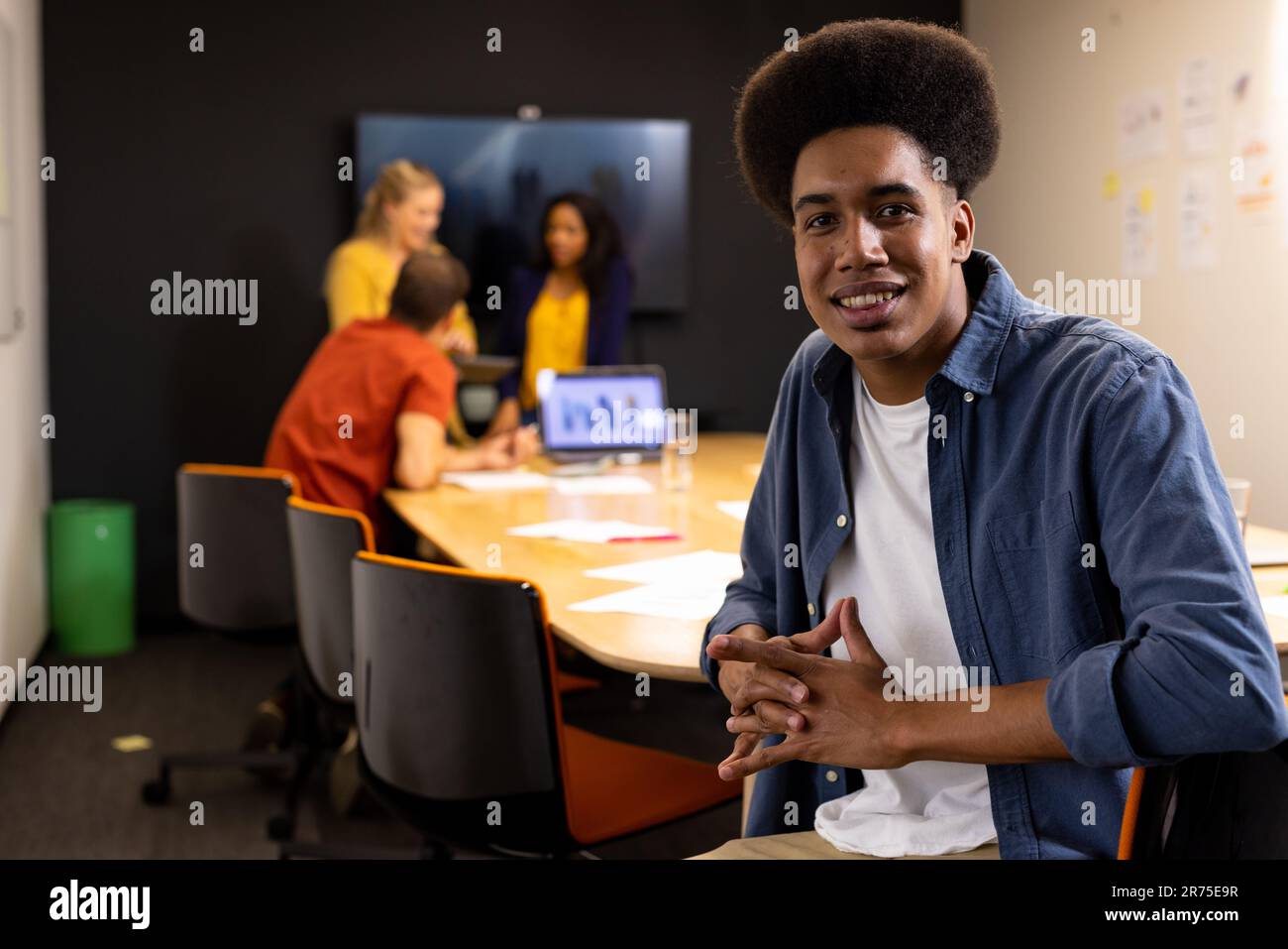 Portrait d'homme d'affaires occasionnel biracial heureux avec afro souriant dans la salle de réunion Banque D'Images