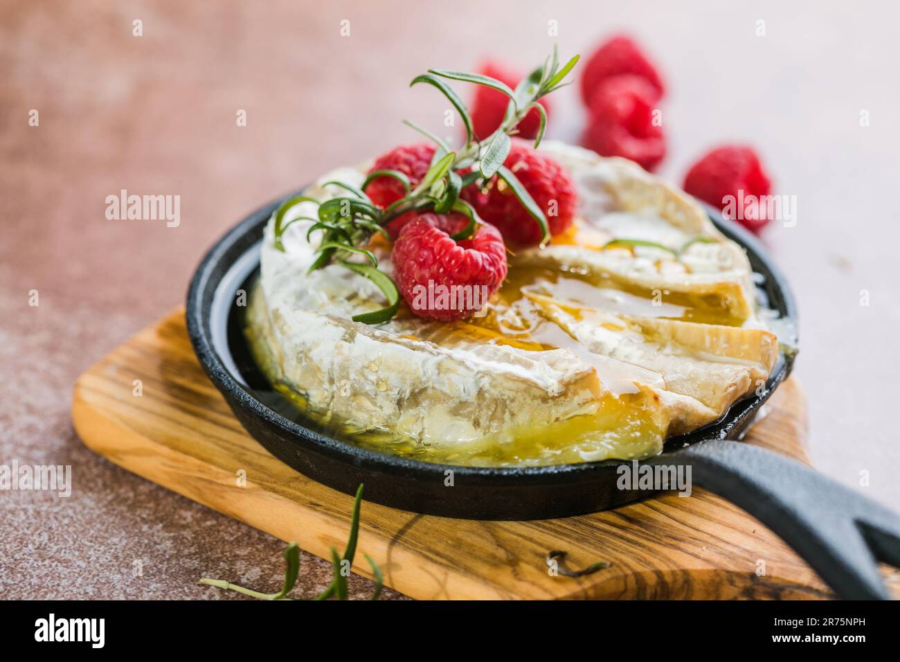 Camembert cuit au four avec feuilles de romarin et framboise. brie grillée  maison sur une table rustique Photo Stock - Alamy