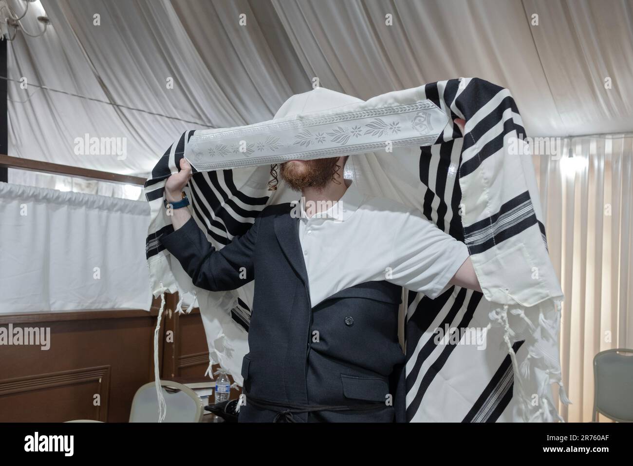 Un juif orthodoxe met sur son châle de prière - tallis - avant les services du matin dans une synagogue de Monsey New York. Banque D'Images