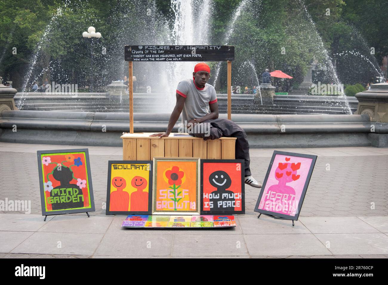 Pose du portrait d'un jeune artiste vendant son œuvre près de la fontaine du parc Washington Square à Greenwich Village à Manhattan. Banque D'Images
