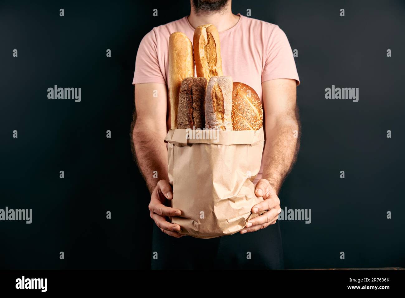 L'homme tient des pains frais de baguettes dans un sac de papier sur fond clair. Boulangerie, concept alimentaire Banque D'Images