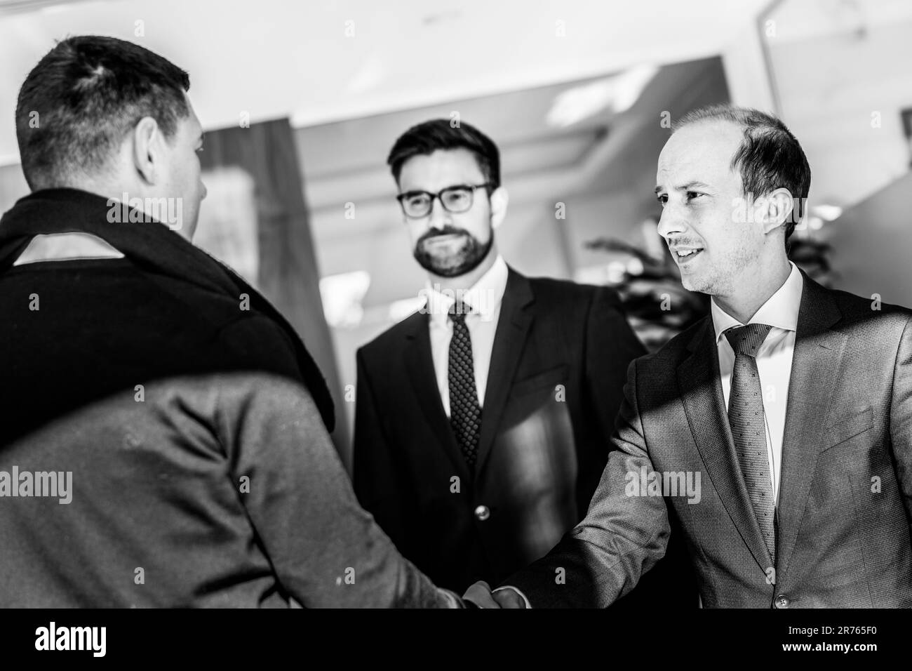 Groupe de professionnels confiants saluant avec une poignée de main lors d'une réunion d'affaires dans un bureau moderne. Conclure l'accord en serrant la main. Image en noir et blanc. Banque D'Images