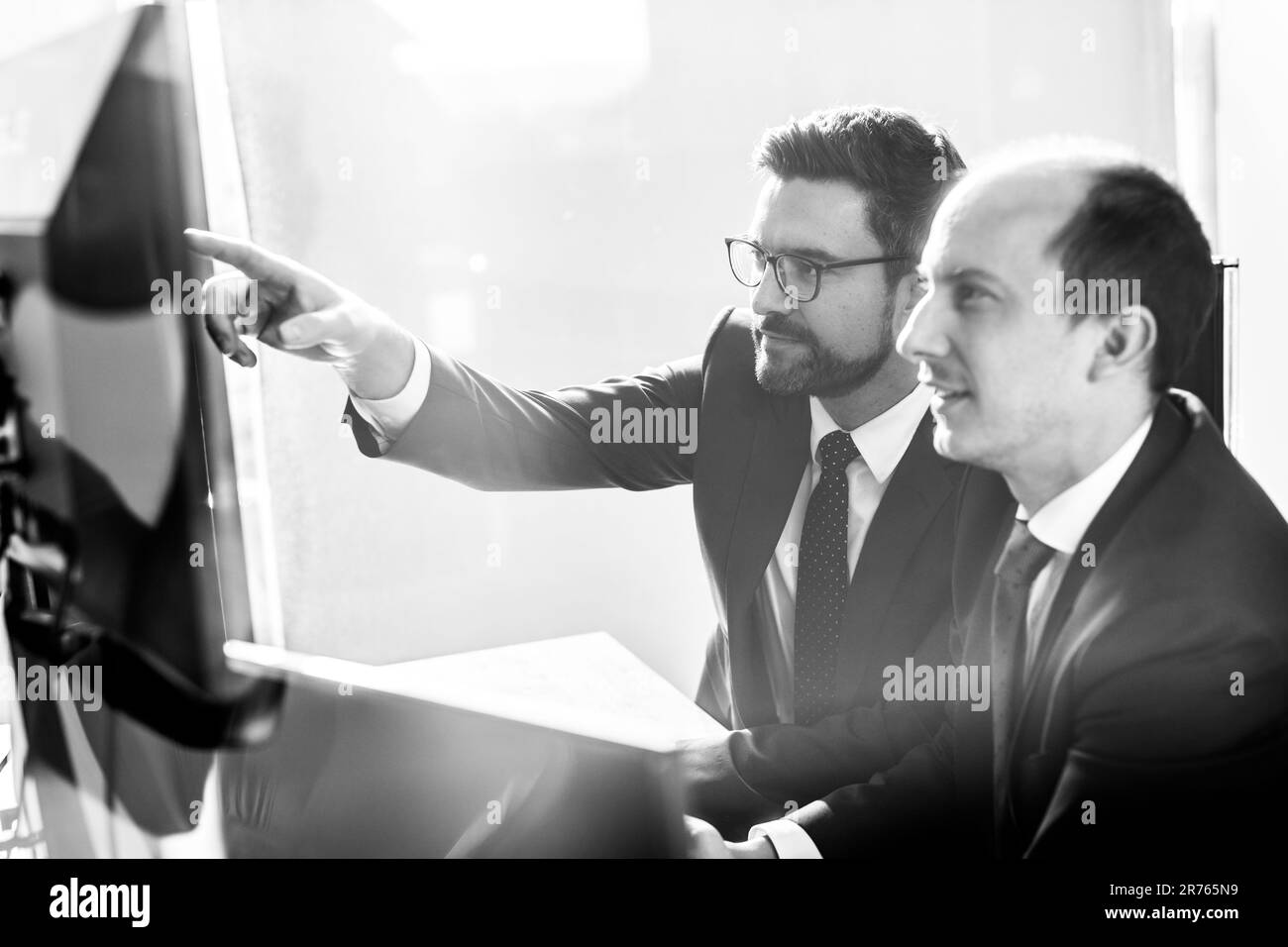 Image de deux hommes d'affaires réfléchis qui regardent des données sur plusieurs écrans d'ordinateur et résolvent des problèmes d'affaires lors de réunions d'affaires dans un bureau d'entreprise moderne.Concept de réussite commerciale. Banque D'Images