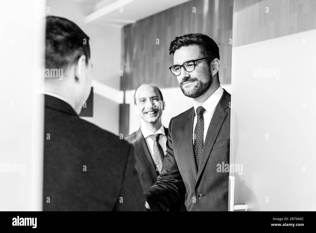 Groupe de professionnels confiants saluant avec une poignée de main lors d'une réunion d'affaires dans un bureau moderne. Conclure l'accord en serrant la main. Image en noir et blanc. Banque D'Images