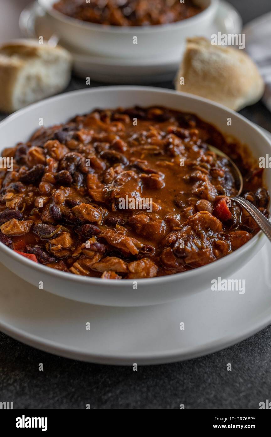 Ragoût de haricots, cuit au four, haricots, viande de poulet et légumes sur une assiette avec une cuillère Banque D'Images