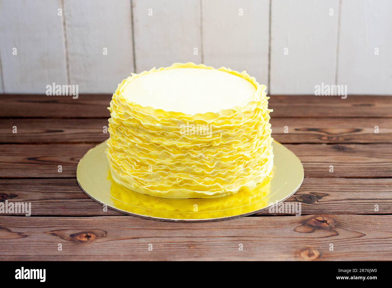 Gâteau jaune aux volants fondants sur fond de bois rustique Banque D'Images
