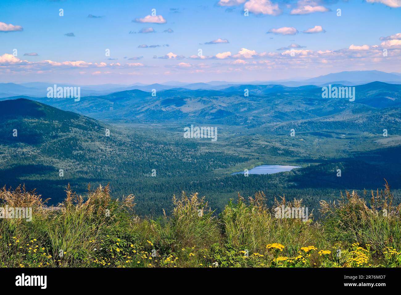 Vue d'été depuis le sommet d'une montagne à Sheregesh (Russie) jusqu'à un terrain montagneux recouvert d'une forêt dense et d'un lac bleu dans la vallée. Herbe a Banque D'Images