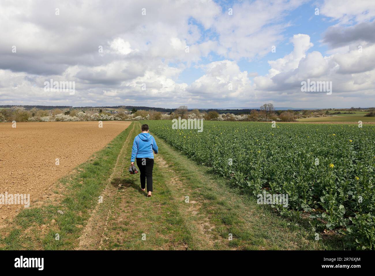 Une femme marche sans chaussures sur une route de terre Banque D'Images