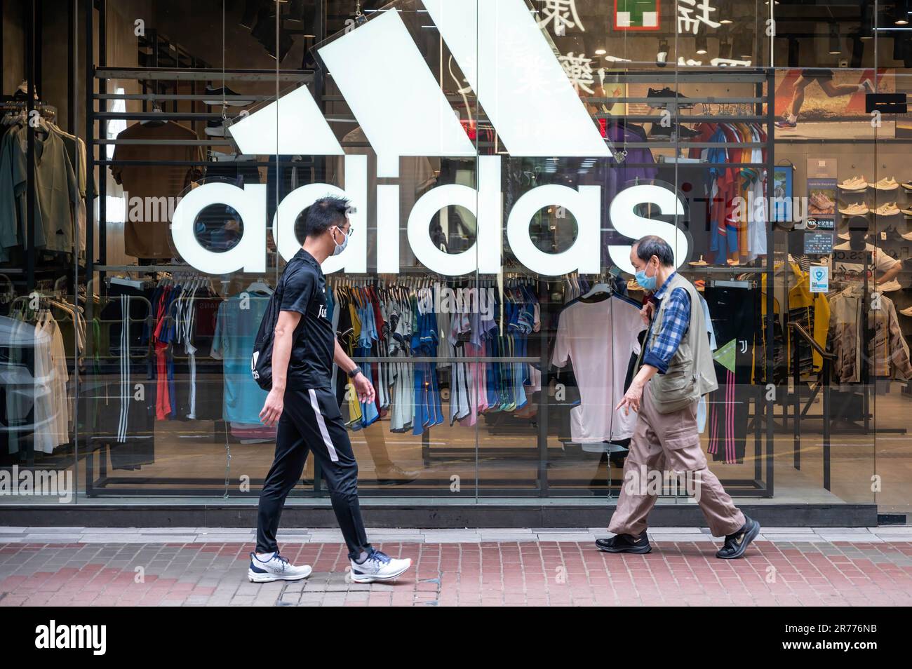 Des piétons marchent devant le magasin Adidas de la marque multinationale allemande de vêtements de sport à Hong Kong. Banque D'Images