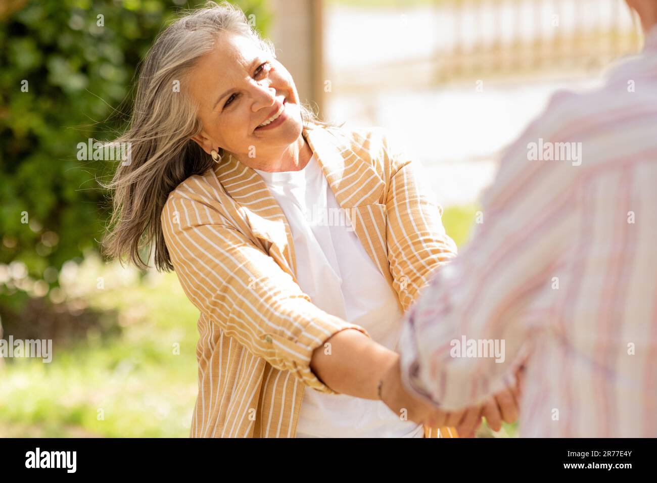 Joyeuse femme européenne mûre grise tient l'homme main, profitez de la date ensemble dans le parc, amusez-vous Banque D'Images