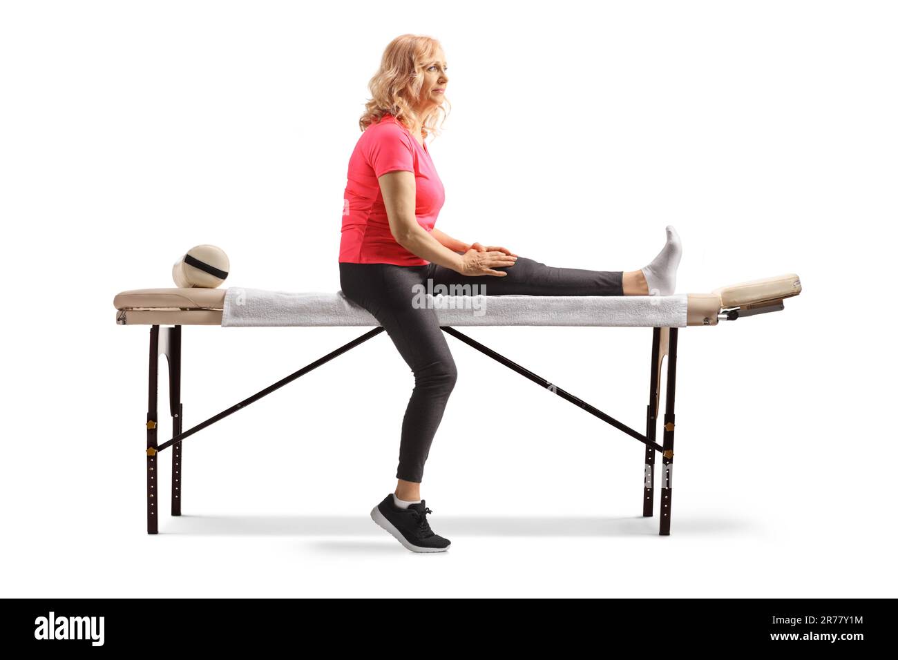 Femme mature avec des pieds blessés assis sur une table de thérapie isolée sur fond blanc Banque D'Images