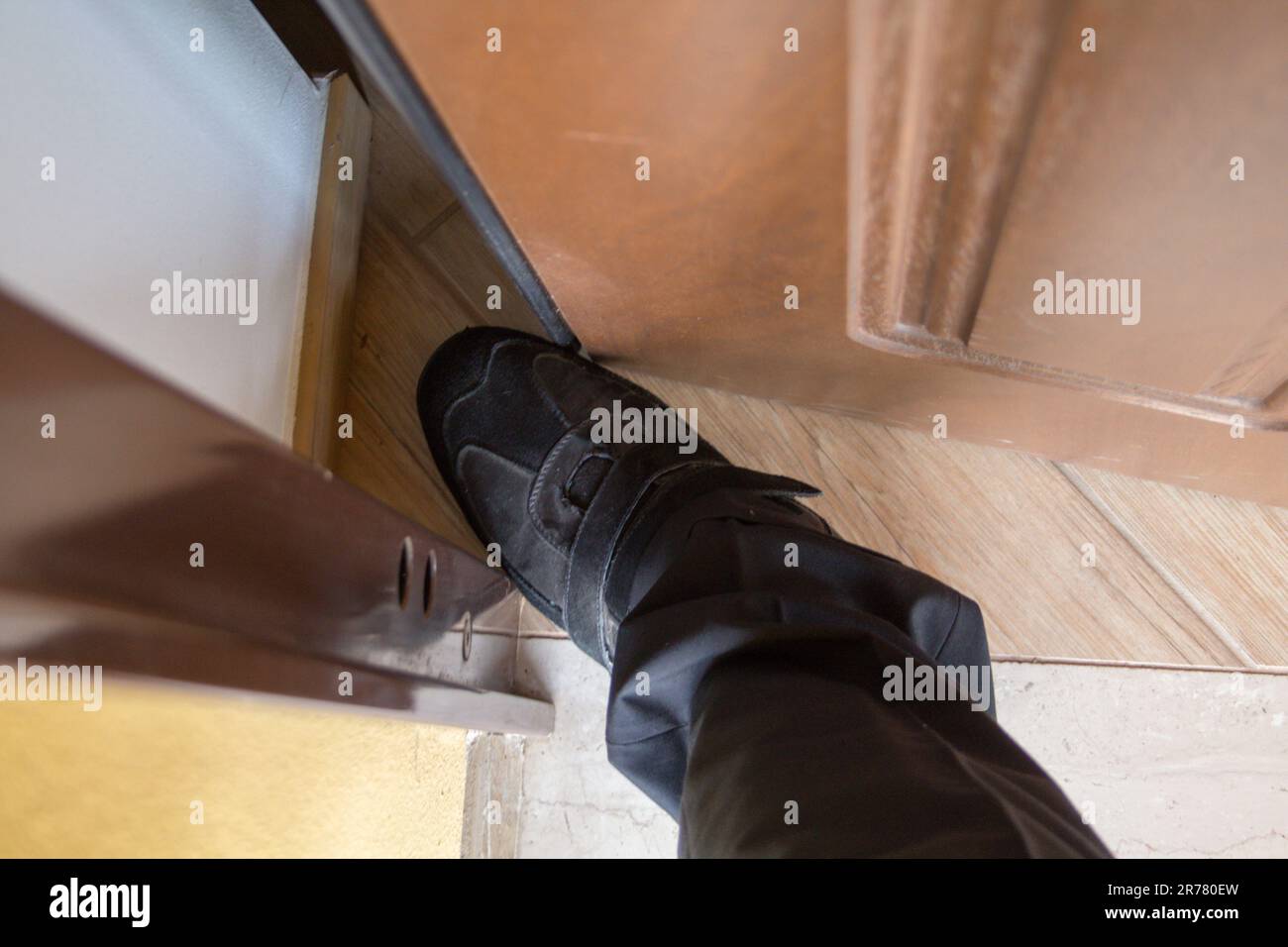 Image de la chaussure et du pied d'un homme au milieu de la porte. Référence aux vendeurs et aux fraudeurs les plus agressifs. Banque D'Images