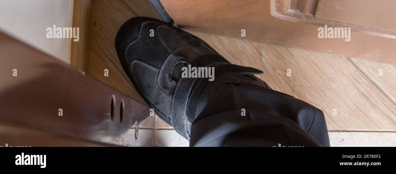 Image de la chaussure et du pied d'un homme au milieu de la porte. Référence aux vendeurs et aux fraudeurs les plus agressifs. Banque D'Images