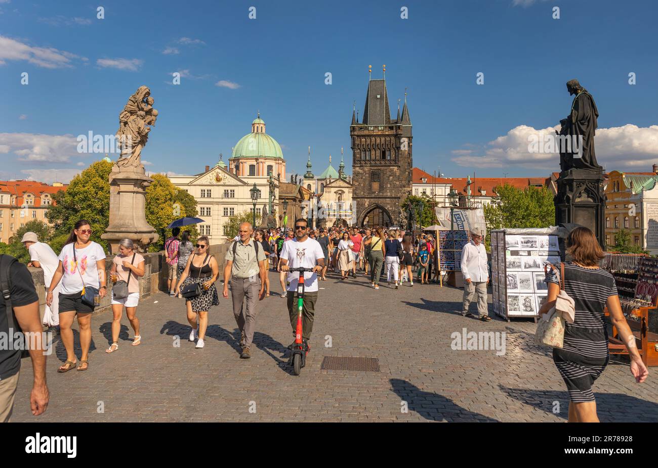 PRAGUE, RÉPUBLIQUE TCHÈQUE - touristes traversant le pont Charles, homme en scooter. Tour du pont de la vieille ville à l'arrière. Banque D'Images
