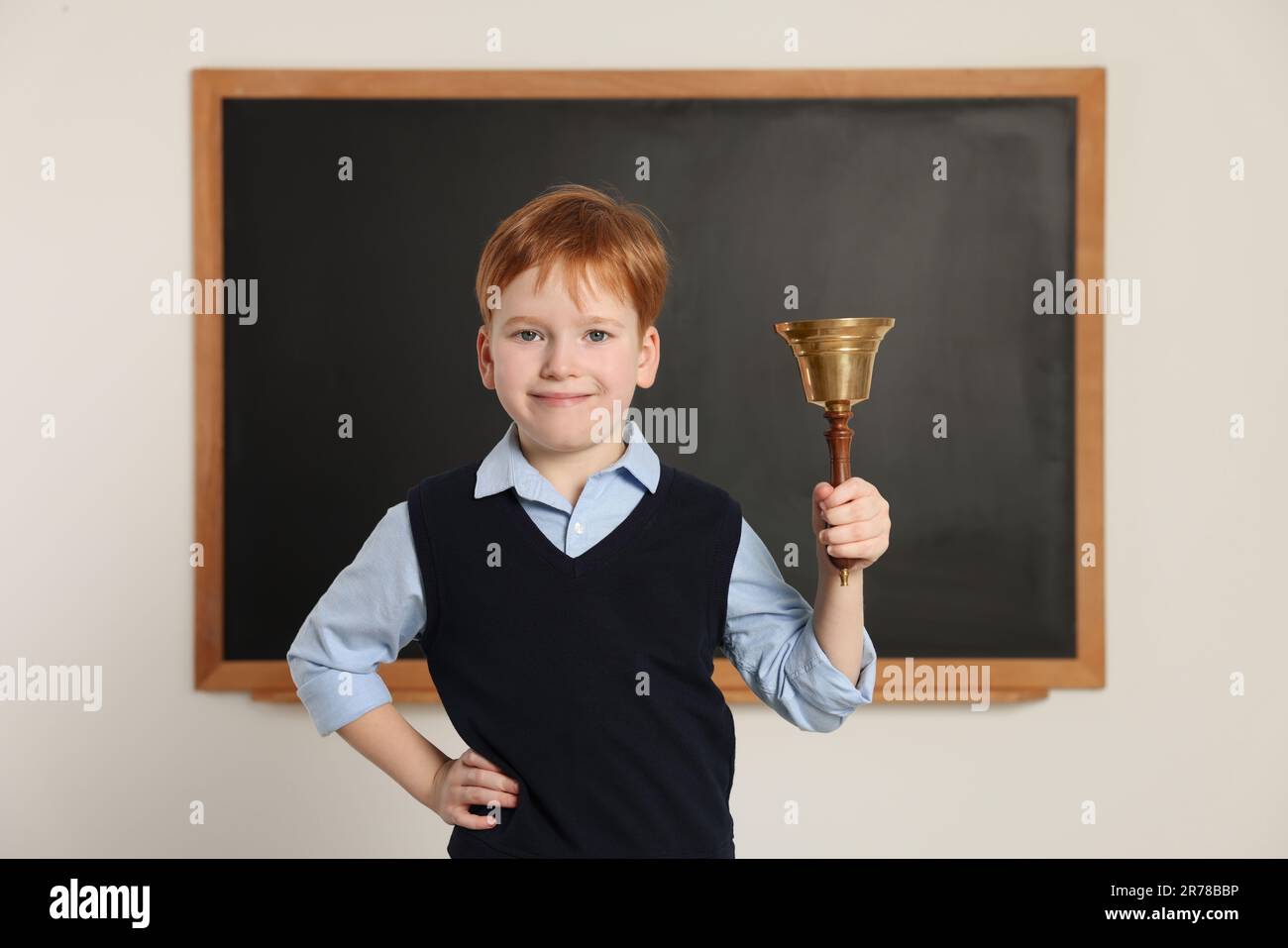 Petit garçon mignon sonnant la cloche de l'école dans la salle de classe Banque D'Images