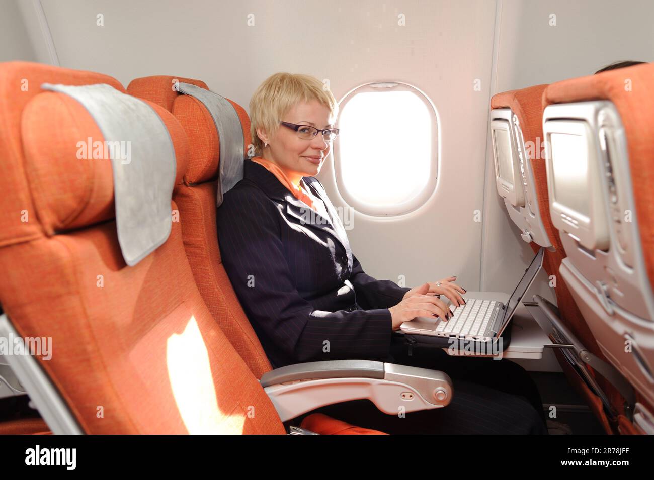 femme d'affaires souriante posant avec un ordinateur portable à bord de l'avion dans la classe d'ecomy d'aeroflot Banque D'Images