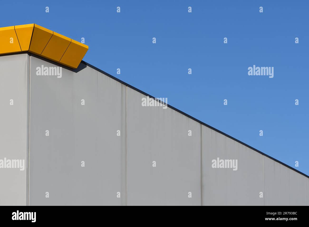 Image abstraite du mur d’un bâtiment avec ciel bleu, métal orange, béton gris, découpage noir avec lignes diagonales et verticales en plein soleil Banque D'Images