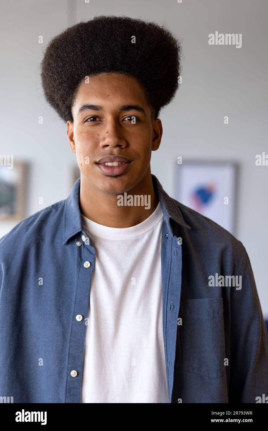 Portrait d'homme d'affaires occasionnel biracial heureux avec afro souriant dans le bureau Banque D'Images