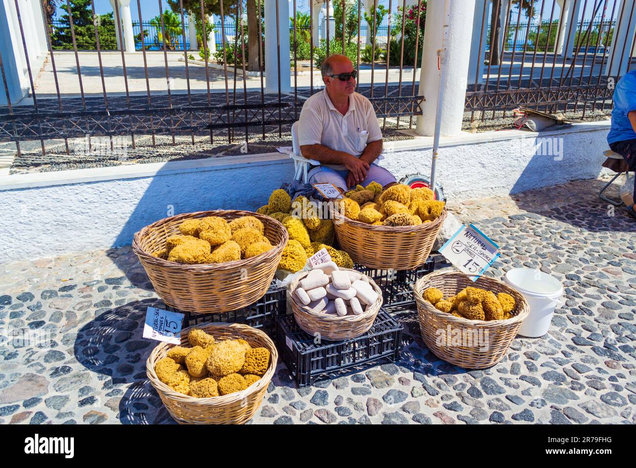 Homme vendant des éponges de mer naturelles de baignade locales dans la rue commerciale principale de Fira-capitale de l'île de Santorini, Grèce Banque D'Images