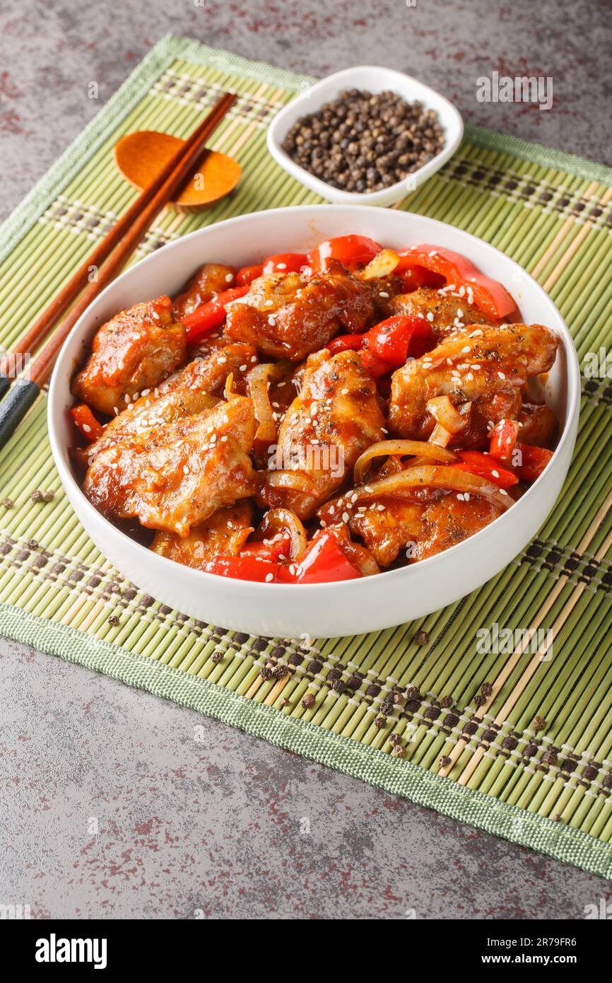 Poulet au poivre noir chinois avec légumes en gros plan dans une assiette sur la table. Verticale Banque D'Images