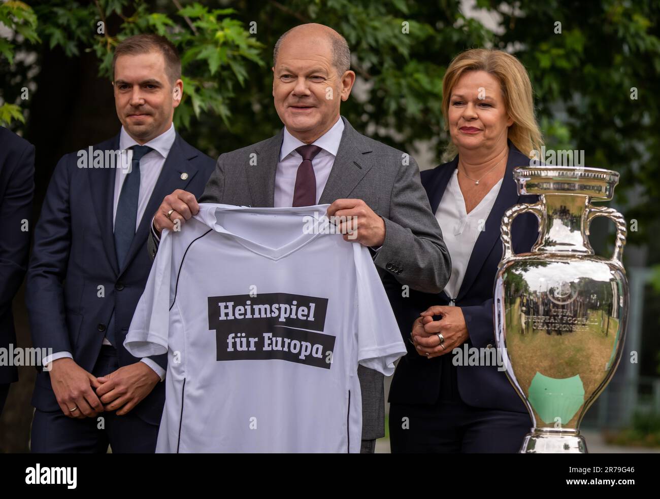 Berlin, Allemagne. 14th juin 2023. Football, EM:, chancelier allemand OLAF Scholz (SPD, M), portant un maillot avec le slogan 'Home Game for Europe,' se dresse entre Philipp Lahm (l), directeur du tournoi, Et Nancy Faeser (SPD), ministre fédérale de l'intérieur, dans le jardin de la Chancellerie à côté de la coupe Henri Delaunay (réplique) du Championnat européen de football. Un an avant le début du Championnat d'Europe 2024 en Allemagne, le DFB fournit des informations sur l'état des préparatifs. Credit: Michael Kappeller/dpa/Alay Live News Banque D'Images
