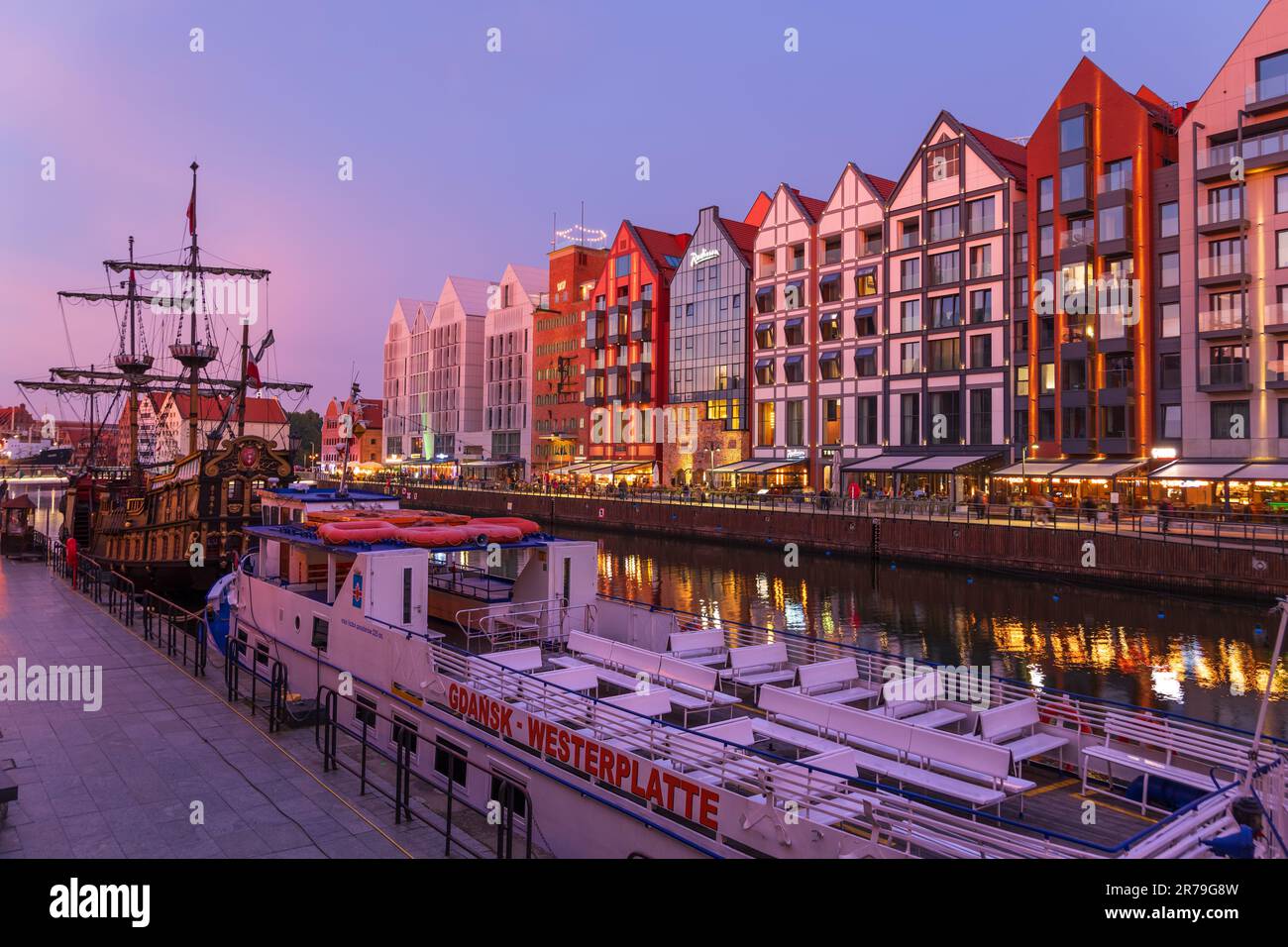 Crépuscule dans la ville de Gdansk en Pologne, bateau de tour de rivière à Westerplatte à long Embankment et bâtiments sur l'île Granary. Banque D'Images
