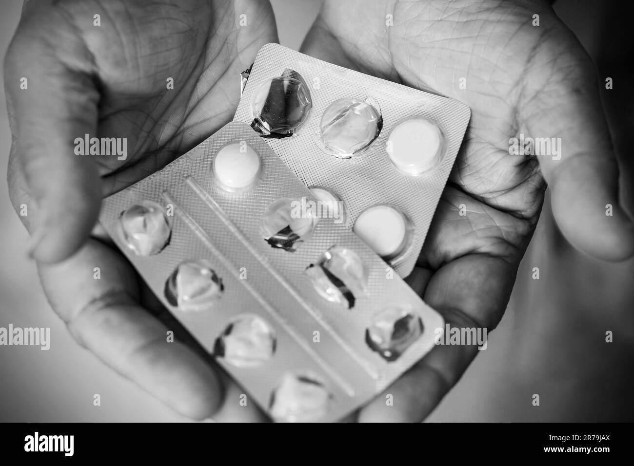 Une photo en noir et blanc des pilules médicales dans les mains d'un homme âgé. Banque D'Images
