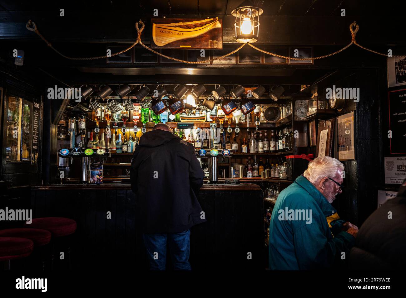 Un client qui attend au bar pour être servi à l'intérieur de l'historique Sloop Inn à St Ives en Cornouailles, en Angleterre, au Royaume-Uni. Banque D'Images