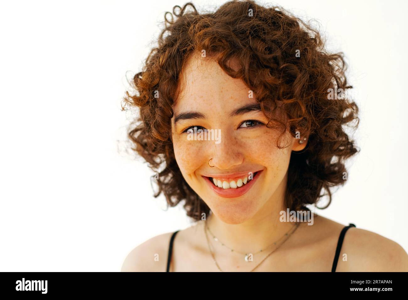 gros plan, jeune femme adulte avec des cheveux bouclés souriant, regardant l'appareil photo Banque D'Images
