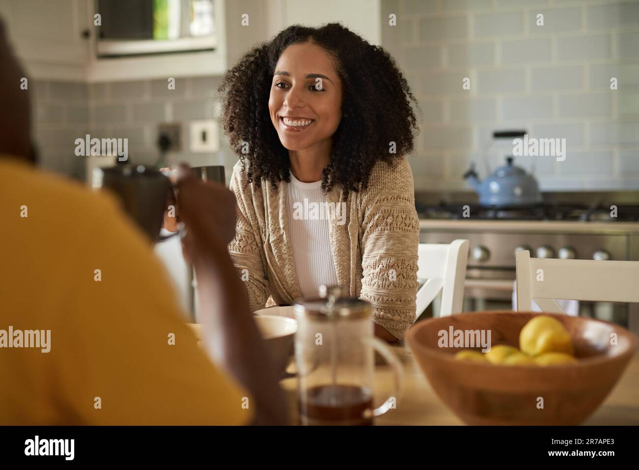 Femme africaine souriante qui boit du café et qui parle avec son mari au petit-déjeuner Banque D'Images