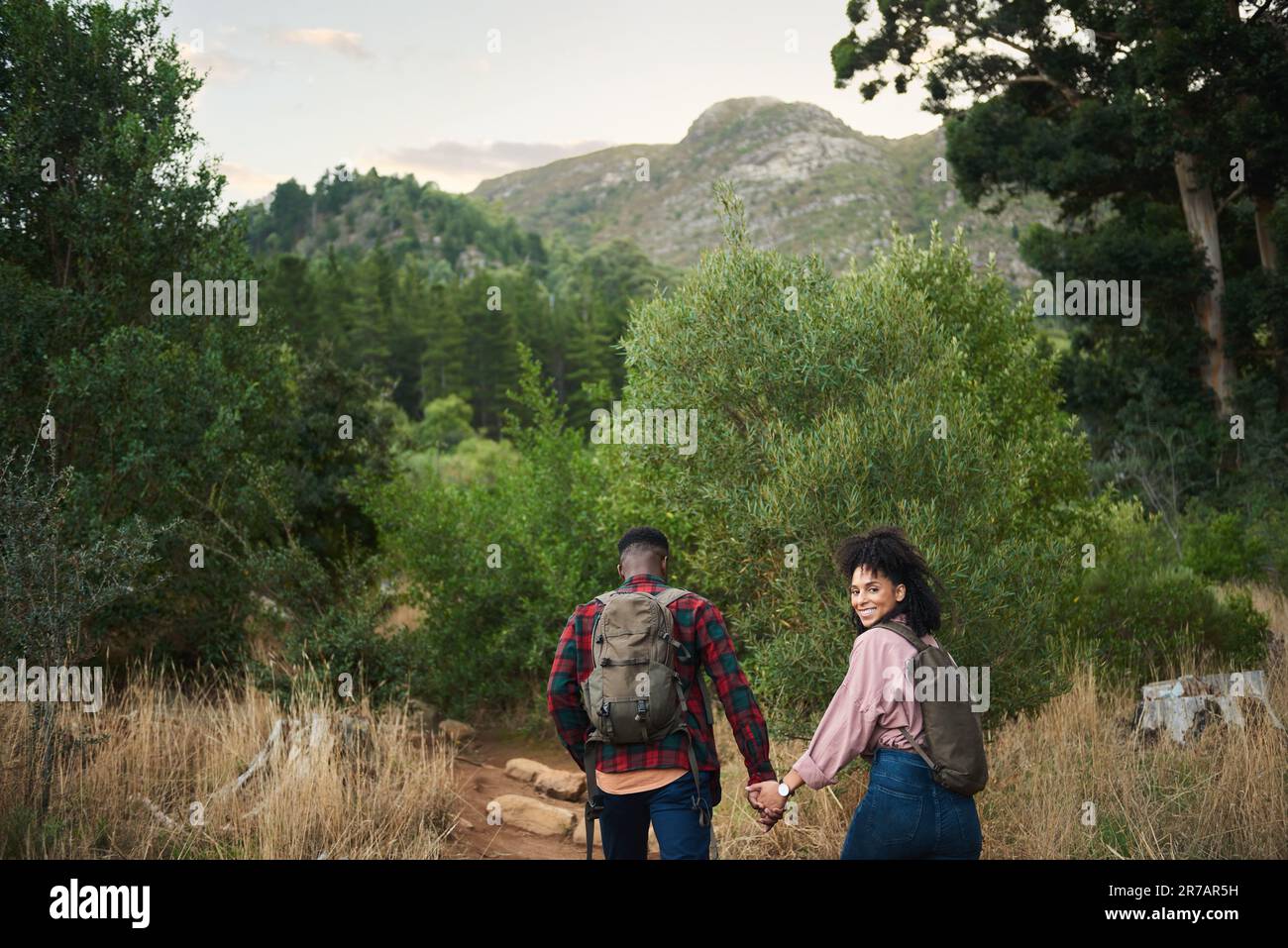 Couple multiracial souriant, randonnée main dans la main le long d'un sentier de nature Banque D'Images