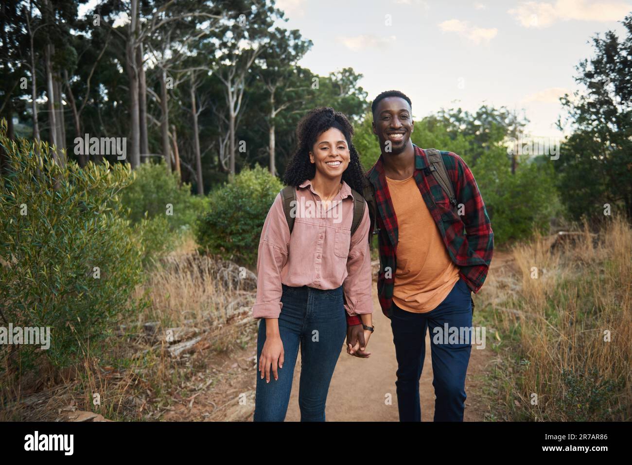 Jeune couple multiethnique souriant debout sur un sentier pendant une randonnée Banque D'Images