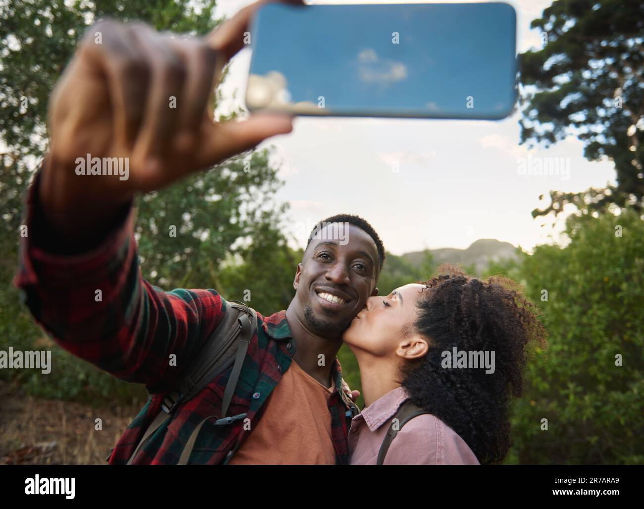 Jeune couple multiethnique souriant et prenant un selfie pendant une randonnée Banque D'Images