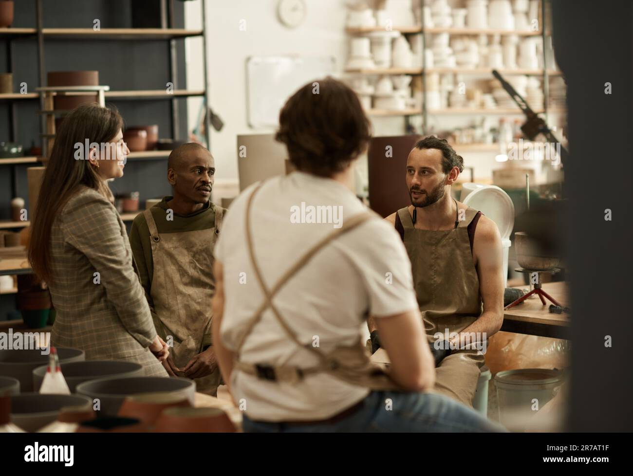 Groupe diversifié de céramistes parlant dans un studio de poterie Banque D'Images