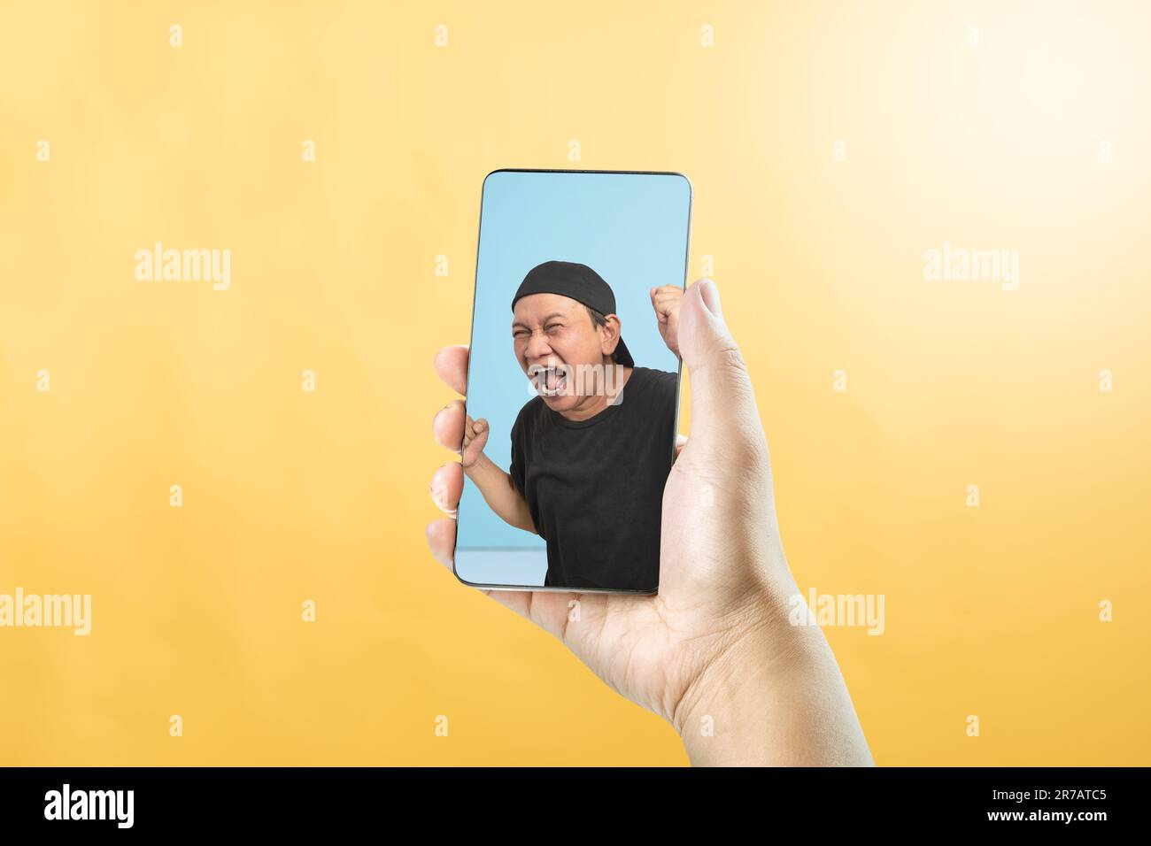 Portrait d'un homme asiatique avec une expression faciale excitée sur l'écran du téléphone portable. Concept de visage souvenir Banque D'Images