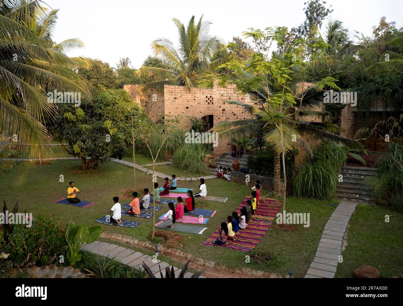 Vue panoramique en fin d'après-midi avec yoga sur la pelouse. Ruines sous-tériennes, Kaggalipura, Bangalore, Inde. Architecte : un seuil Architectes, 2023. Banque D'Images