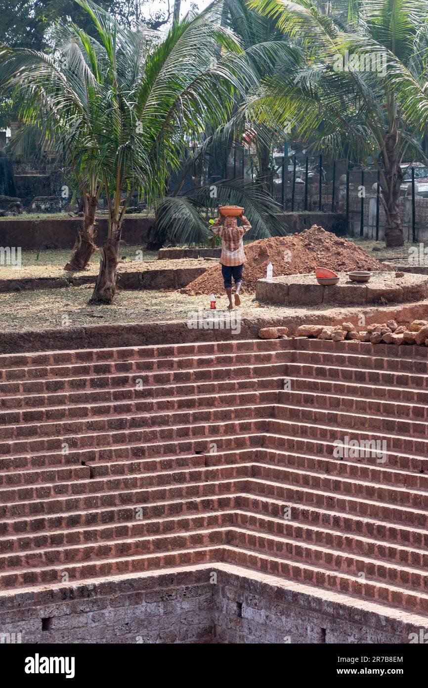 Old Goa, Inde - janvier 2023 : un ouvrier travaillant à la restauration d'un ancien puits de STEP sur le site du patrimoine de l'UNESCO d'Old Goa. Banque D'Images