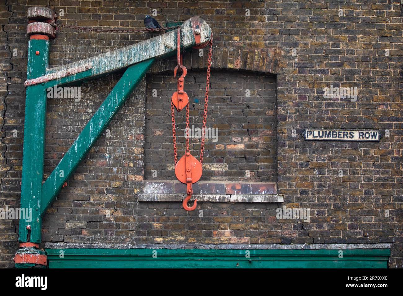 Vue sur un ancien palan et le panneau indiquant Plumbers Row, situé juste à côté de la route Whitechapel à Tower Hamlets, Londres, Royaume-Uni. Banque D'Images