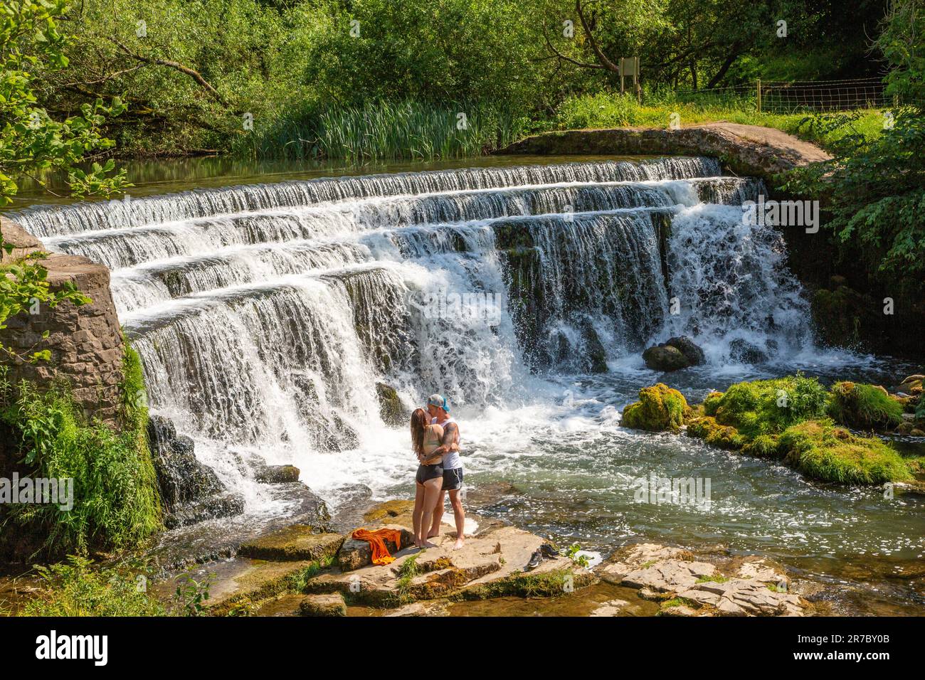 Un jeune couple a embrassé et embrassé sous une cascade sur la rivière Wye dans le district de Monsall Dale Peak Derbyshire pendant la vague de chaleur de 2023 Banque D'Images