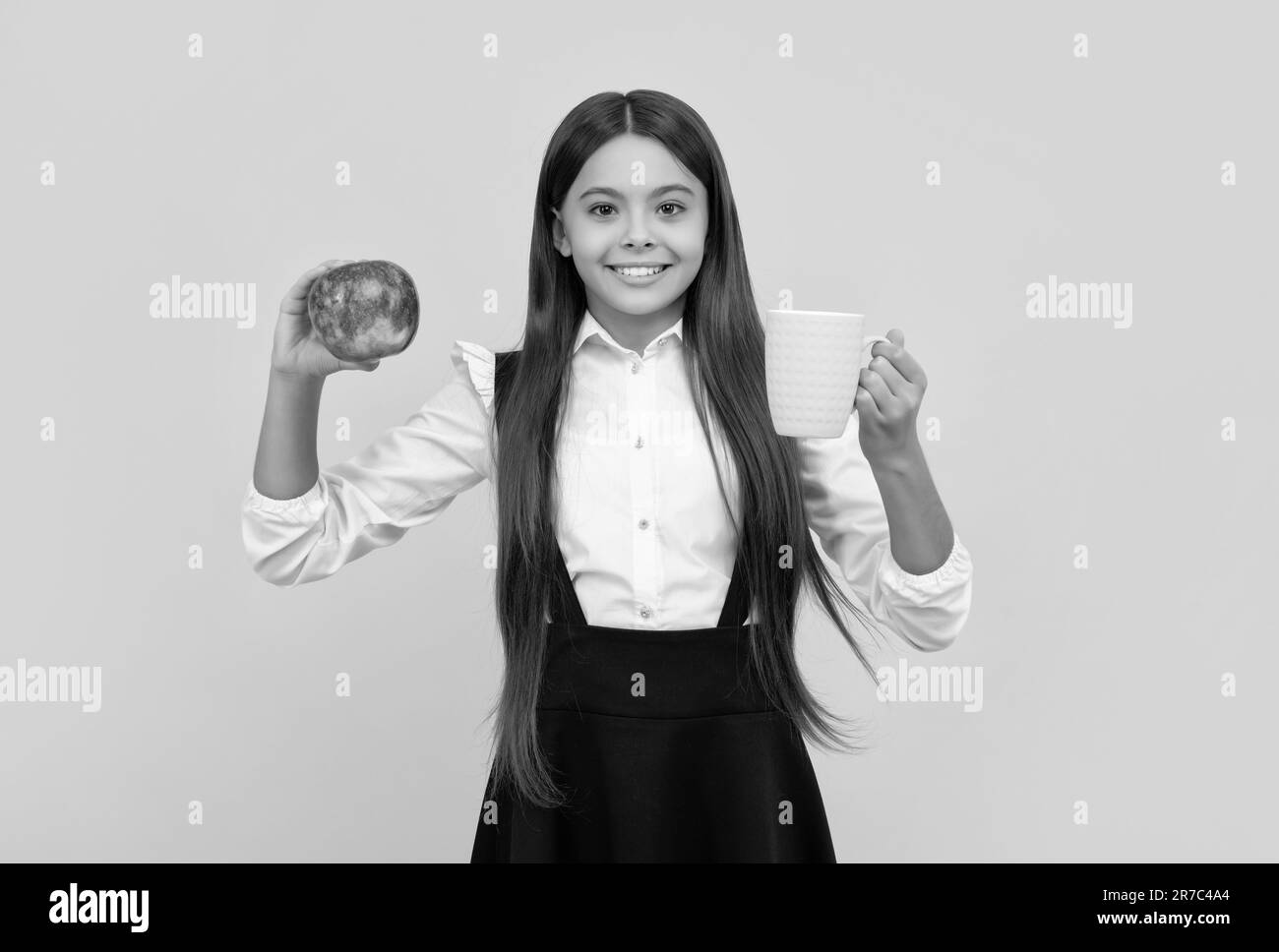 joyeux enfant de l'école en uniforme tenir la pomme et bouteille d'eau, bien-être Banque D'Images