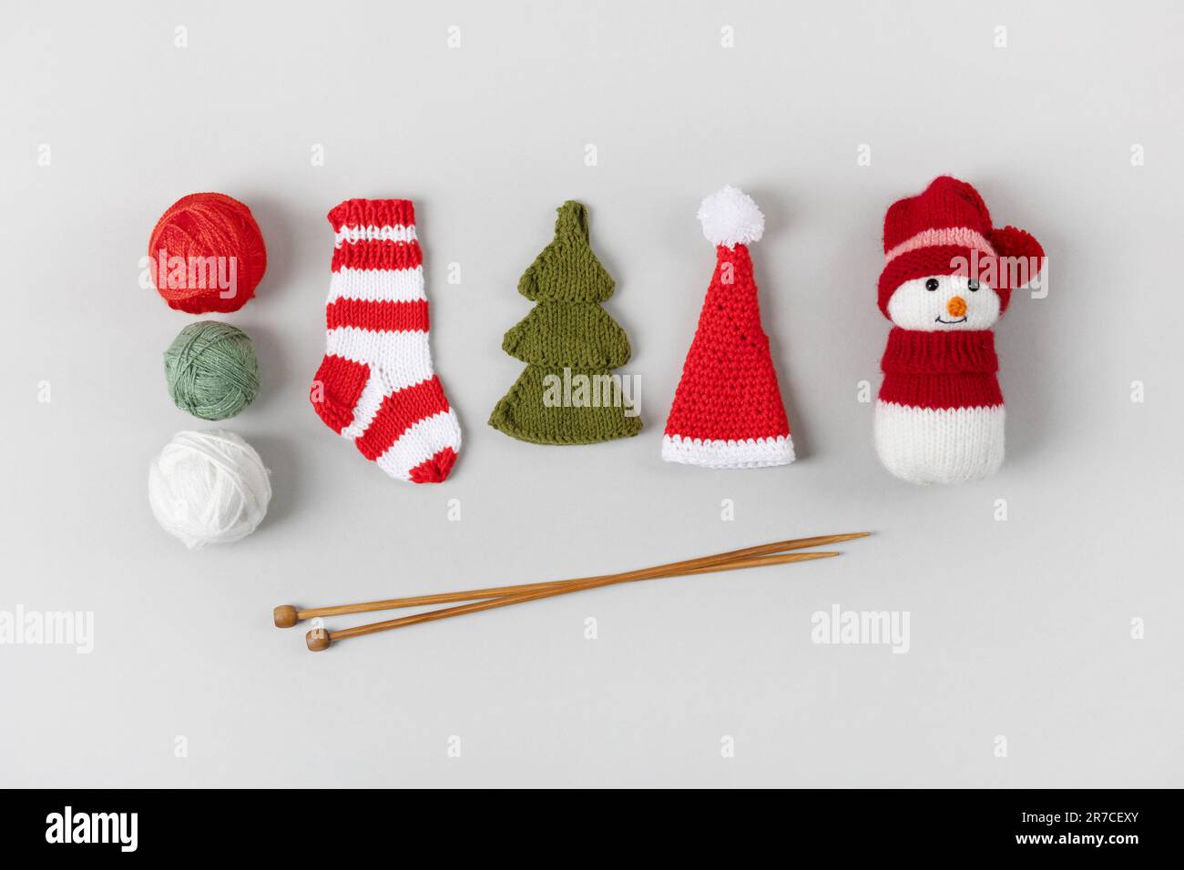 Cadeaux de tricotage pour les vacances d'hiver. Chaussette de Noël rayée en maille, bonhomme de neige, chapeau de Père Noël et sapin de Noël vert avec boules de fil et de tricot Banque D'Images