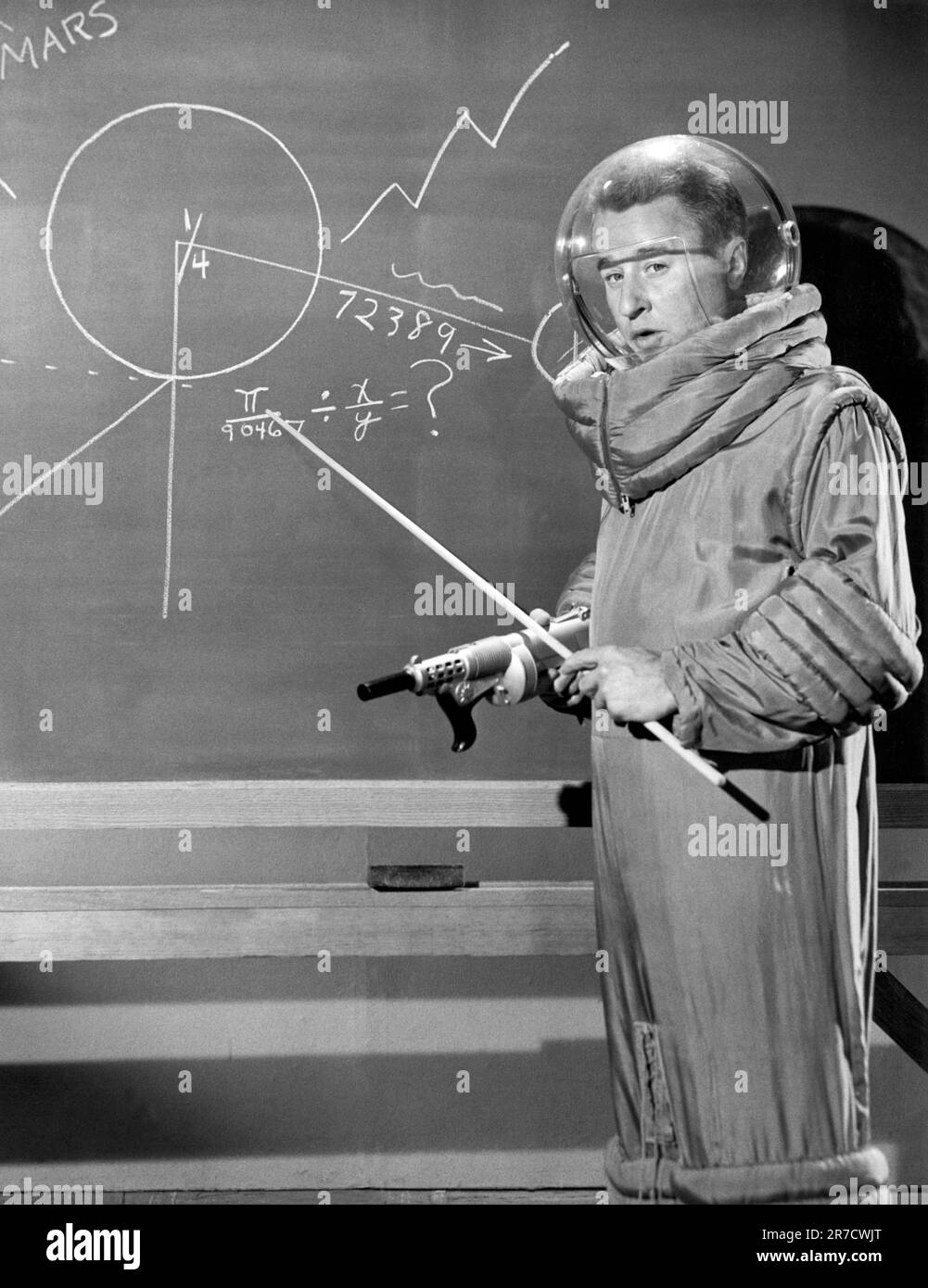Hollywood, Californie: c. 1958 acteur et comédien George Gobel portant un ensemble spatial en se tenant à un tableau noir d'école. Banque D'Images