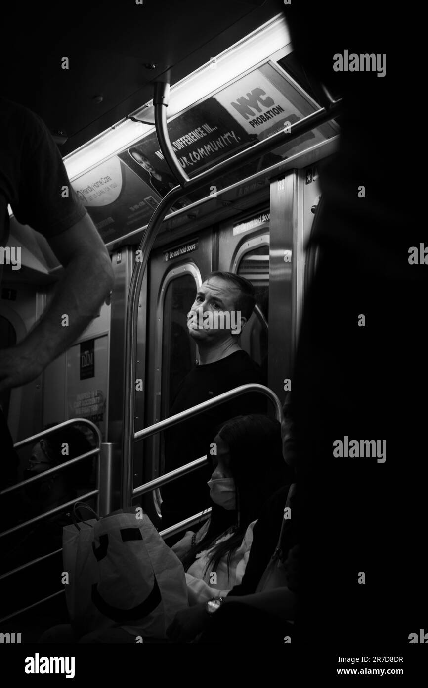 Un jeune homme adulte est assis dans un train de transport en commun tandis qu'une adolescente se détend sur un banc à proximité Banque D'Images