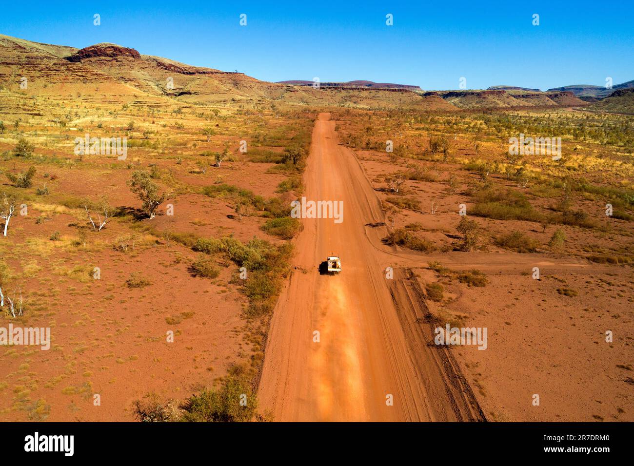 Vue Arial d'une voiture voyageant sur une route rouge poussiéreuse dans l'Outback australien, Pilbara, Australie occidentale Banque D'Images