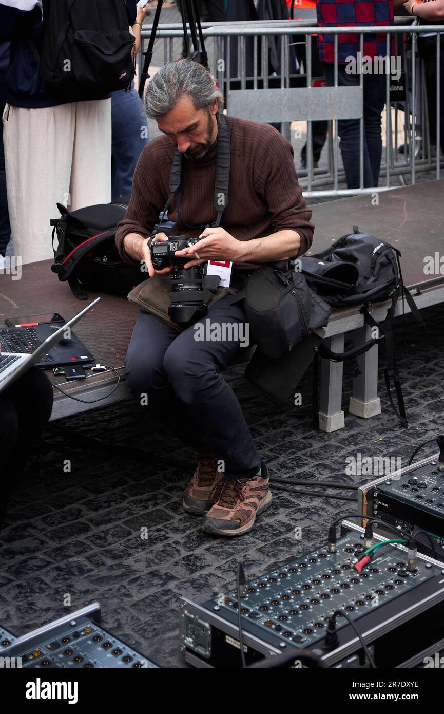 Barcelone - 15 juin 2023: Photographe de presse assis et entouré d'équipement électronique examinant ses images sur l'appareil photo. Banque D'Images