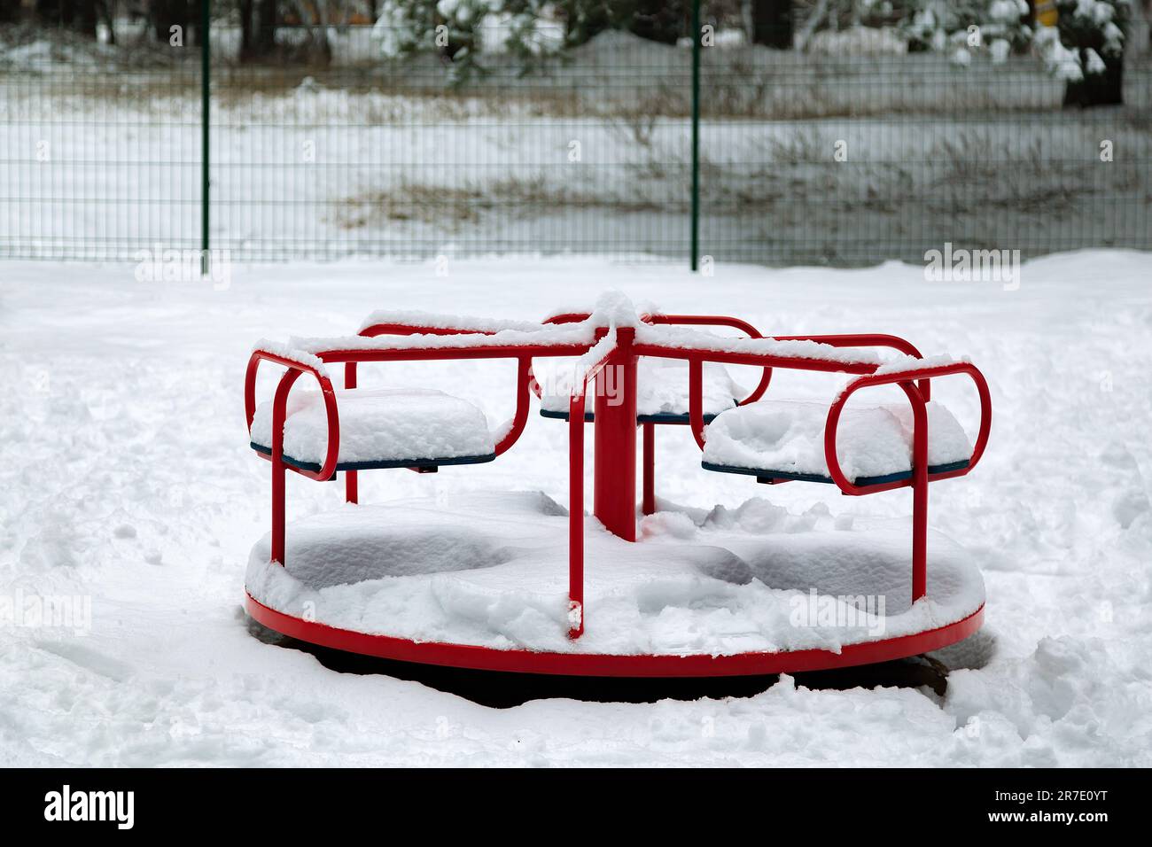 Neige sur une balançoire pour enfants après une forte chute de neige. carrousel pivotant. Scène urbaine de la vie urbaine en hiver dans une tempête de neige. L'hiver sur l'aire de jeux. Jeu Banque D'Images