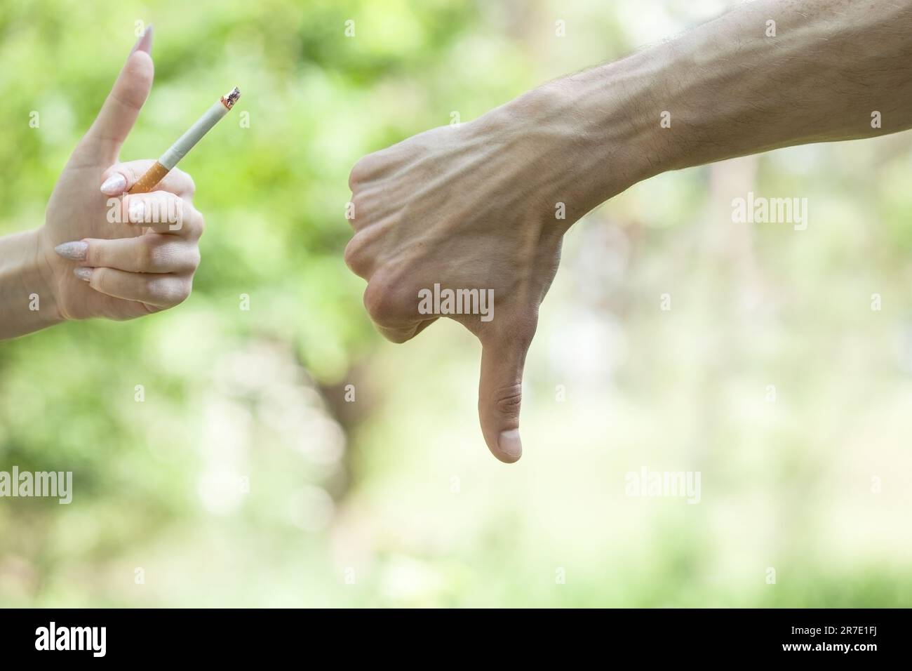 Le jour du sevrage tabagique.la main de l'homme dit non, une cigarette. Pouce vers le bas. Main féminine tenant une cigarette.Stop fumer et concept de santé Banque D'Images