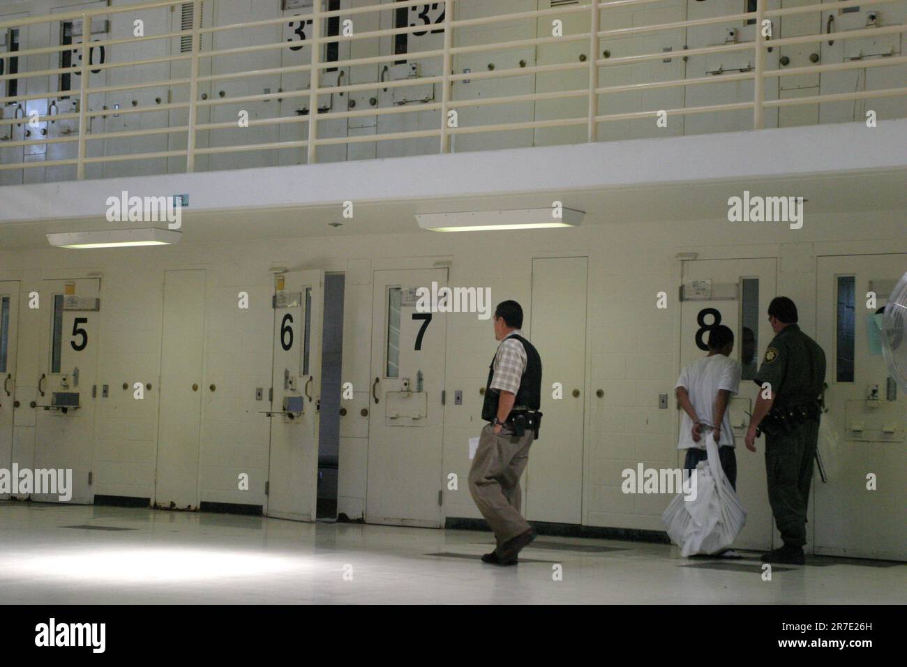 Groupe de détenus adultes de sexe masculin dans un bloc cellulaire de prison ouvert, chaque porte étant numérotée Banque D'Images