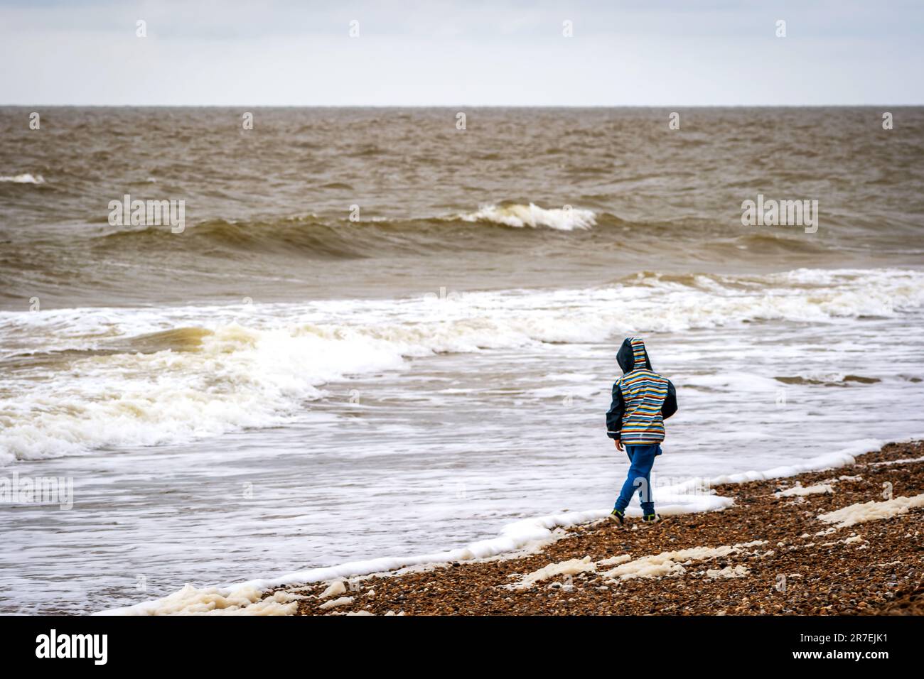 enfant garçon jetant la pierre dans la mer en angleterre royaume-uni. Banque D'Images