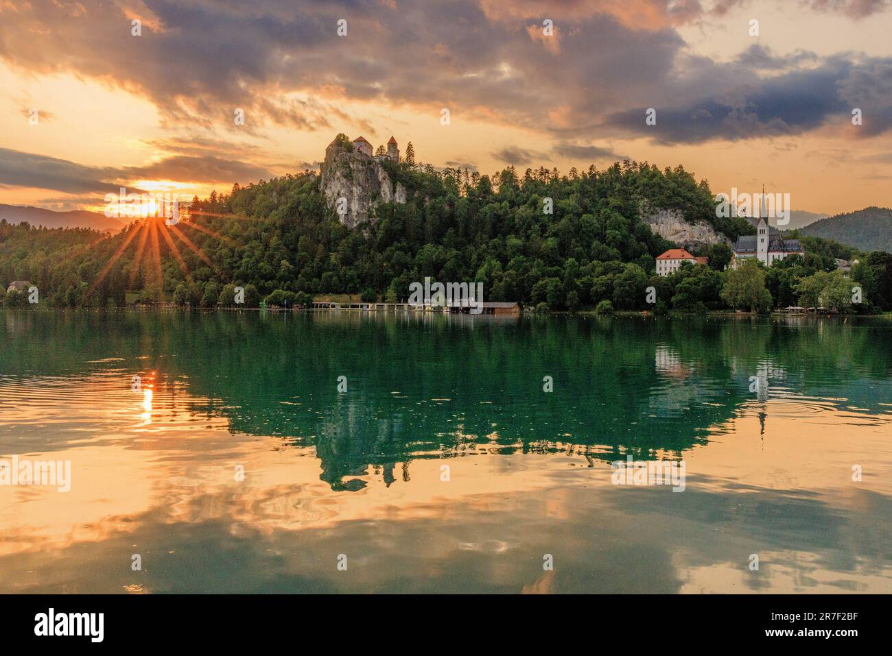 l'effet sunburst tandis que le soleil se couche derrière le château de bled fait une belle scène de château de bled et l'église st martin reflétée dans le lac de bled Banque D'Images